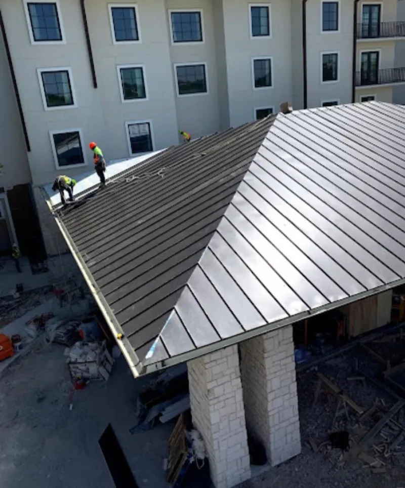 Crew installing standing seam metal roof panels on a commercial project in Farmington